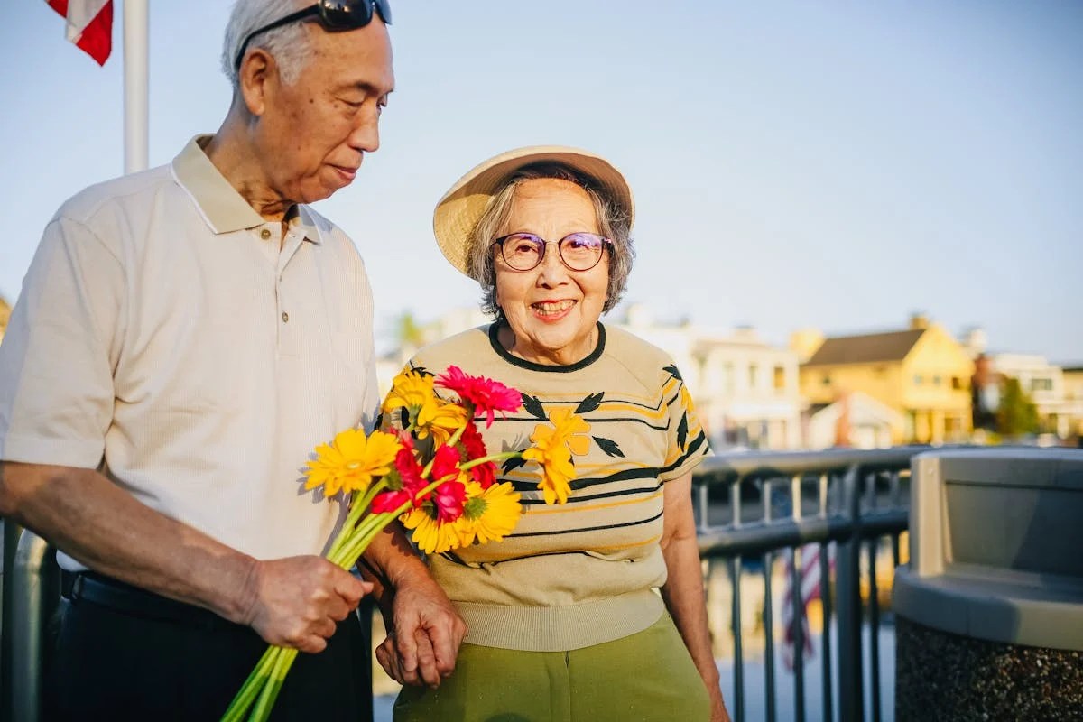 old couple, man is holding flowers and the woman is smiling